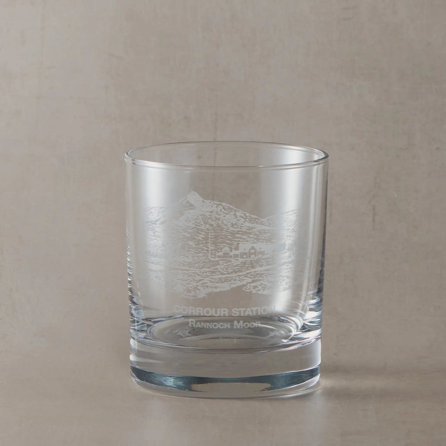 Clear whisky glass engraved with Corrour Station and Rannoch Moor landscape, photographed on a soft neutral background