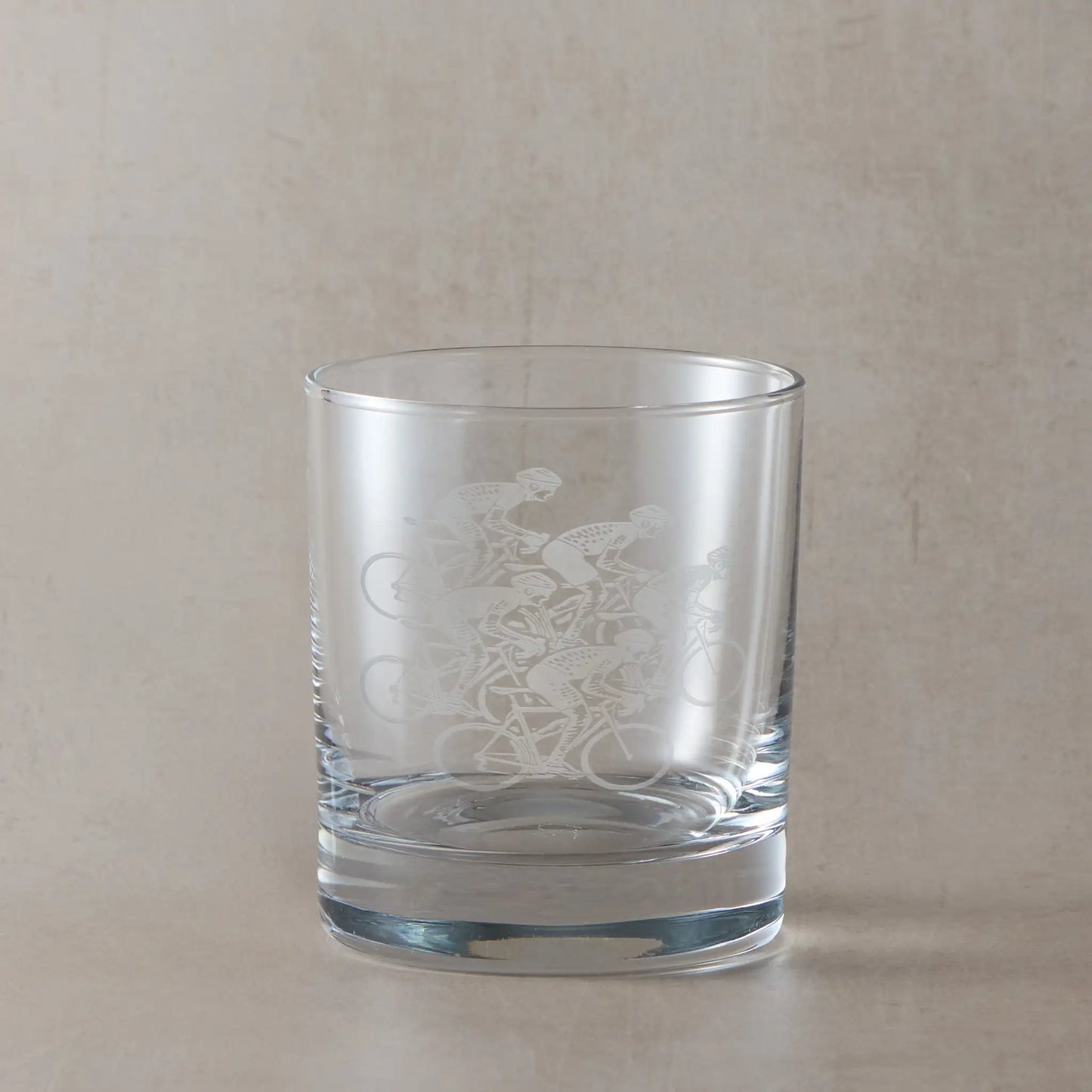 Whisky glass with five road cyclists racing design on a beige background