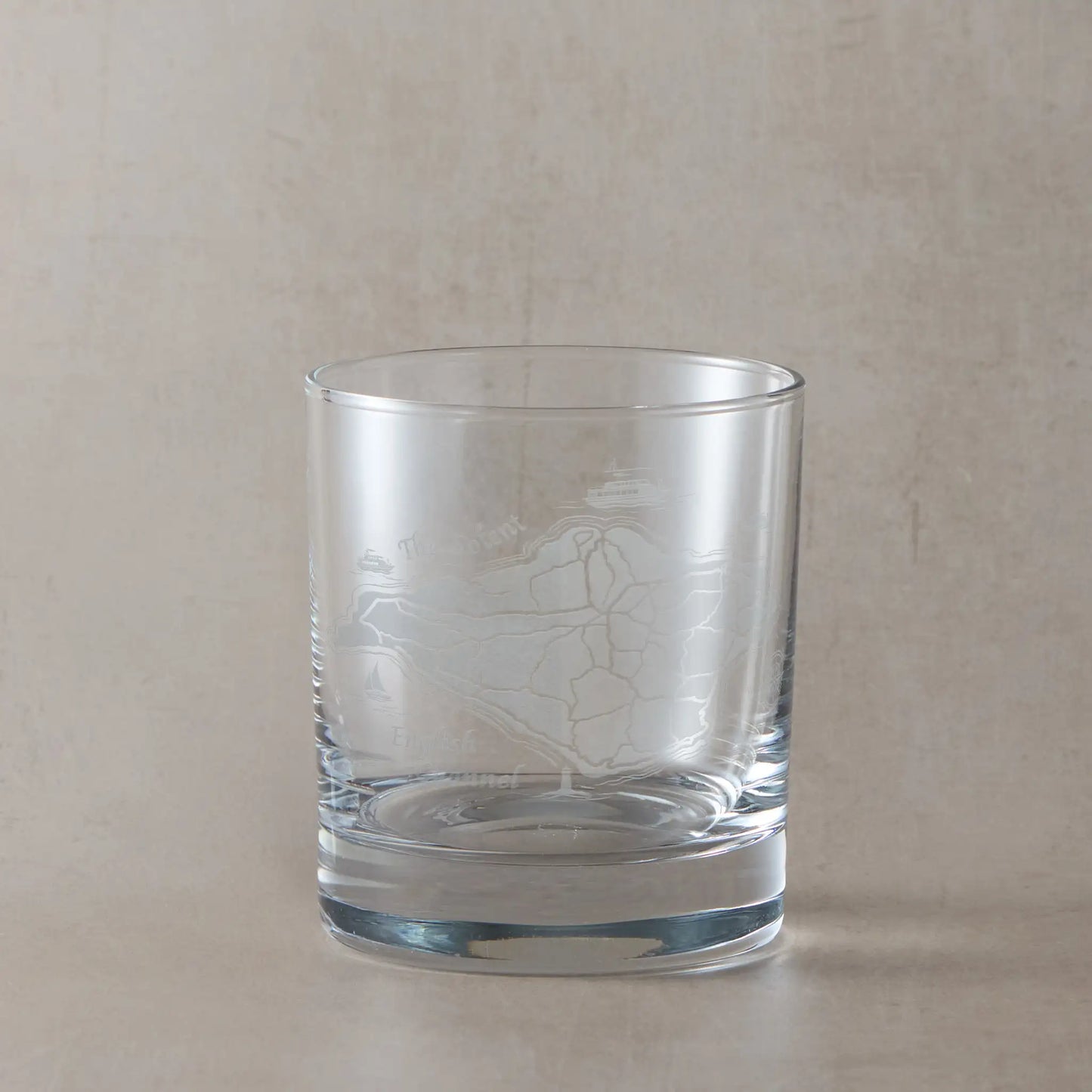 Clear whisky glass with engraved Isle of Wight map on a beige background