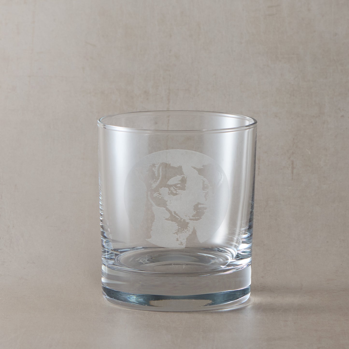 Whisky glass with engraved portrait of a Jack Russell Terrier, on a beige background