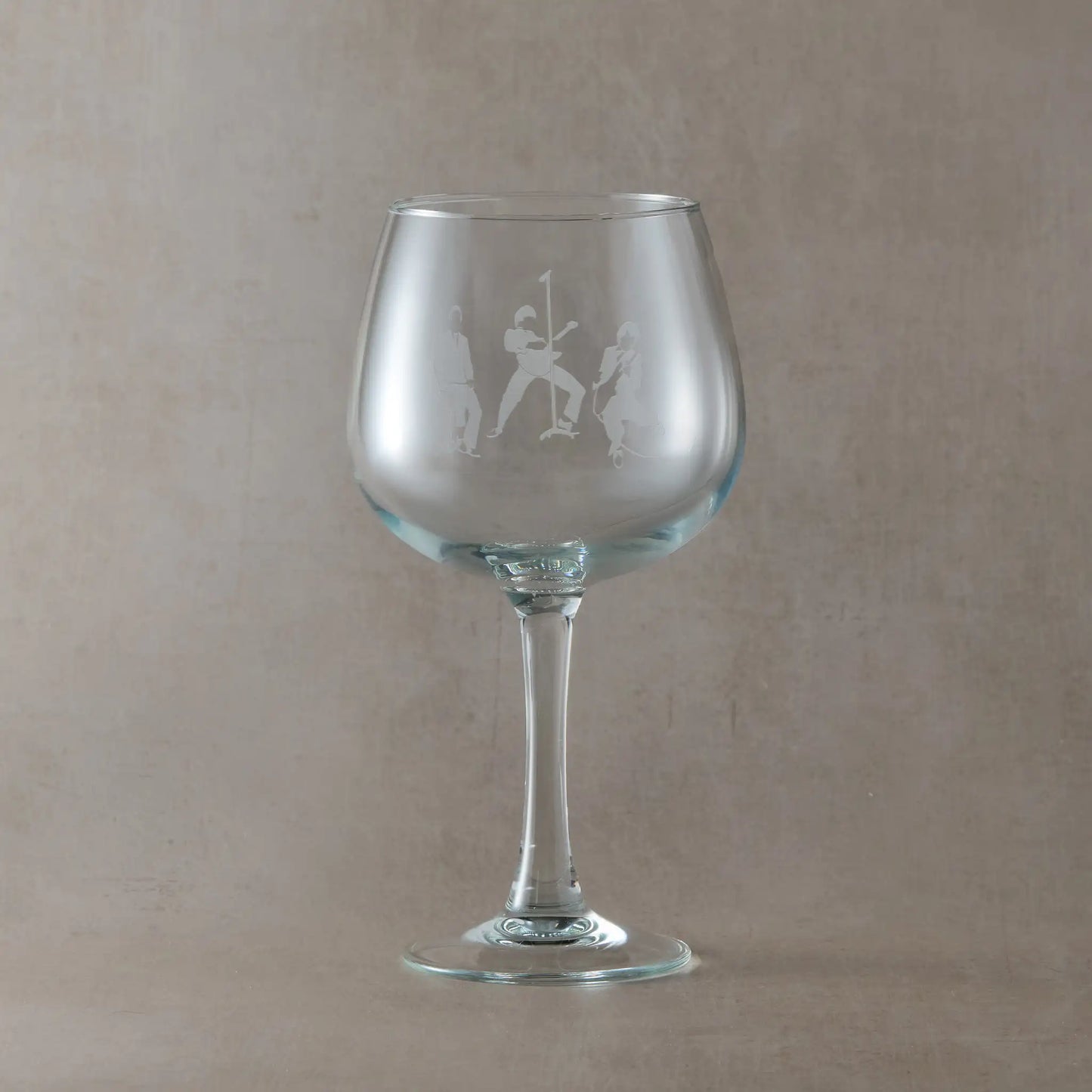 Gin glass engraved with the The Jam band members silhouettes, on a beige background