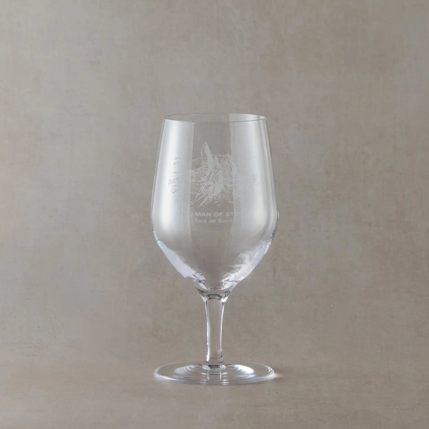 Clear mineral water glass with engraved Old Man of Storr design on a beige background