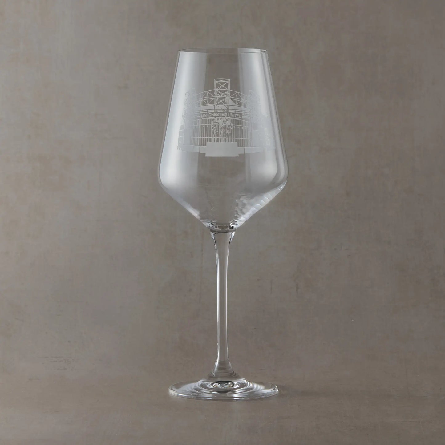 Wine glass with engraved Old Trafford design on a light background