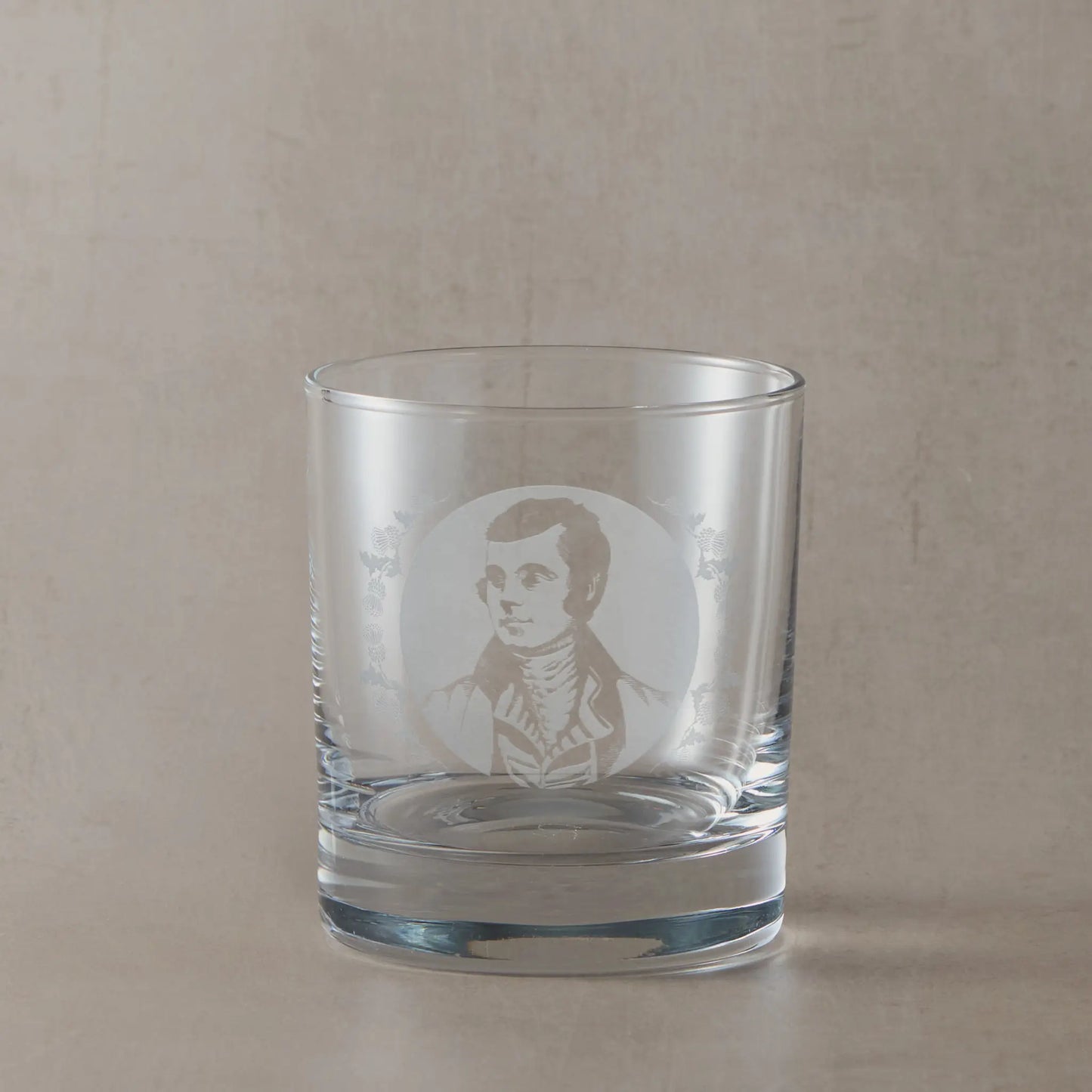 Portrait of the Scottish poet Robert Burns engraved into a whisky glass with thistle design