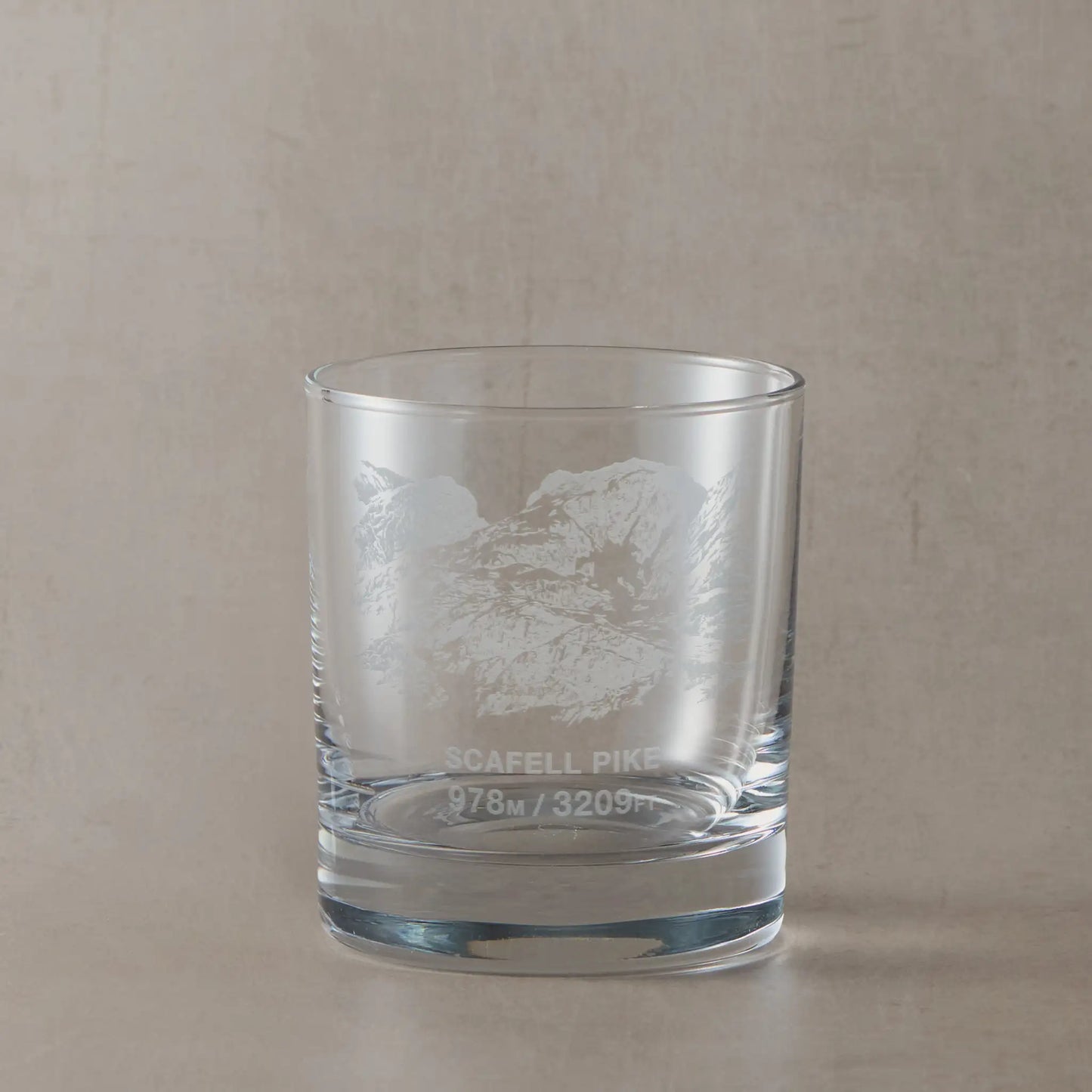 Whisky glass engraved with Scafell Pike, photographed on a neutral coloured background