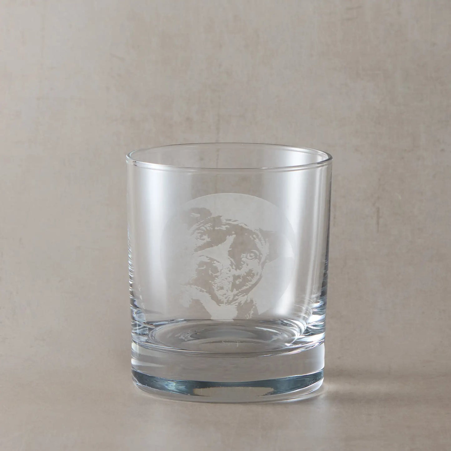 Whisky glass with engraved portrait of a Staffordshire Bull Terrier, on a beige background