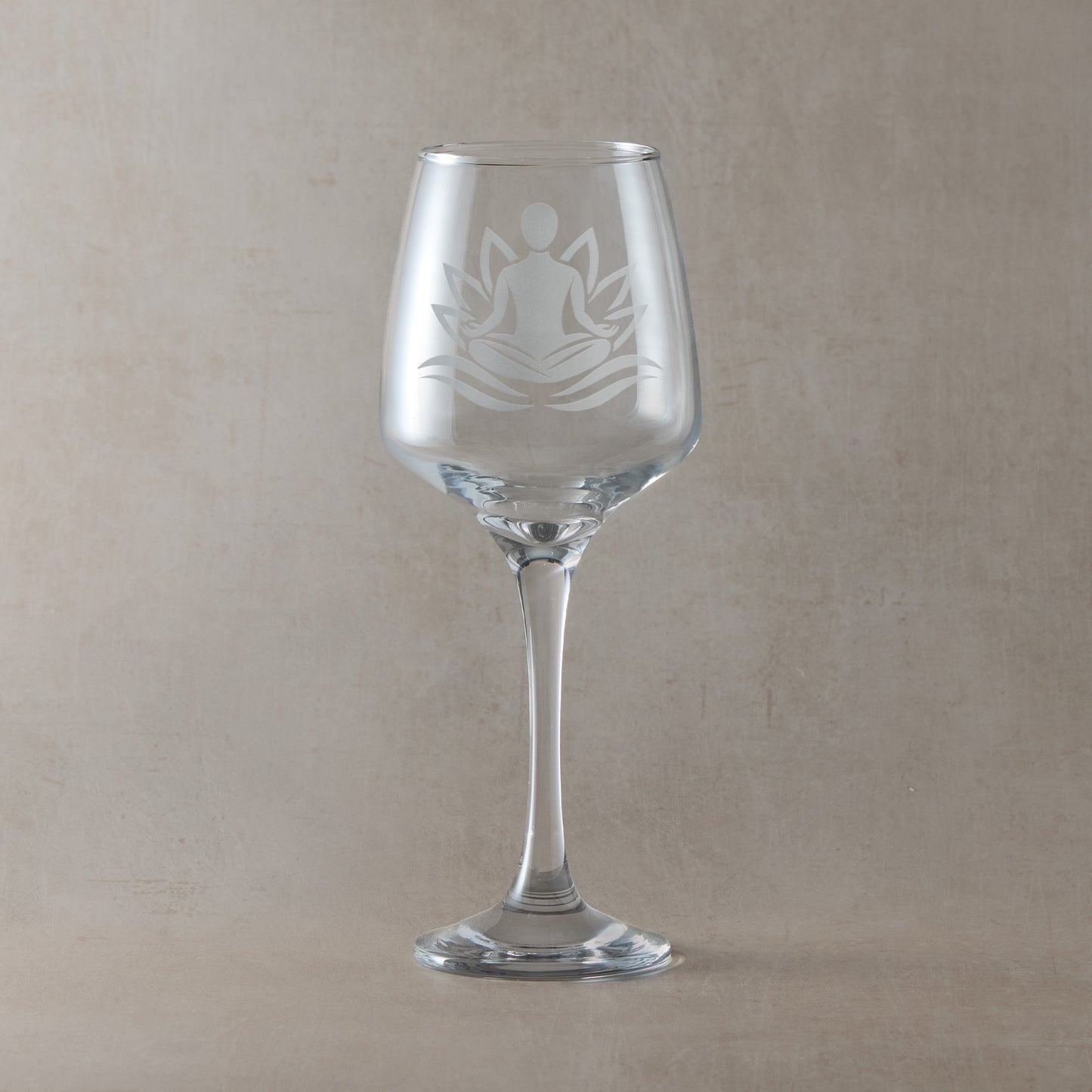 Wine glass engraved with a male figure practicing Yoga set against a lotus flower