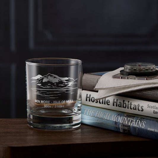 Clear whisky glass engraved with the scottish mountain Ben More placed next to  a stack of books