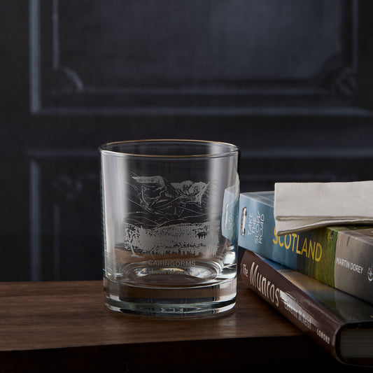 Cairngorms whisky glass with engraved Loch Morlich design on a wooden surface with books in the background