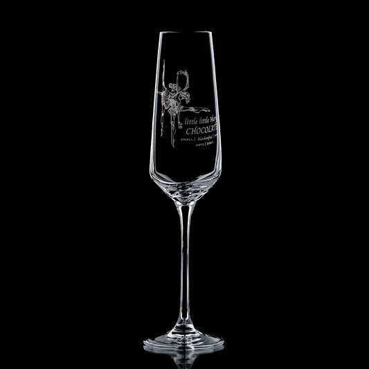 Clear glass champagne flute with engraved corporate logo design on a black background