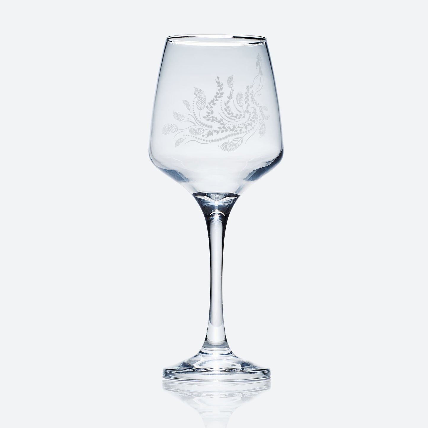 Engraved wine glass featuring a peacock with flowing tail of feathers and trailing leaves, inspired by Pittencrieff Park’s flora on a white background