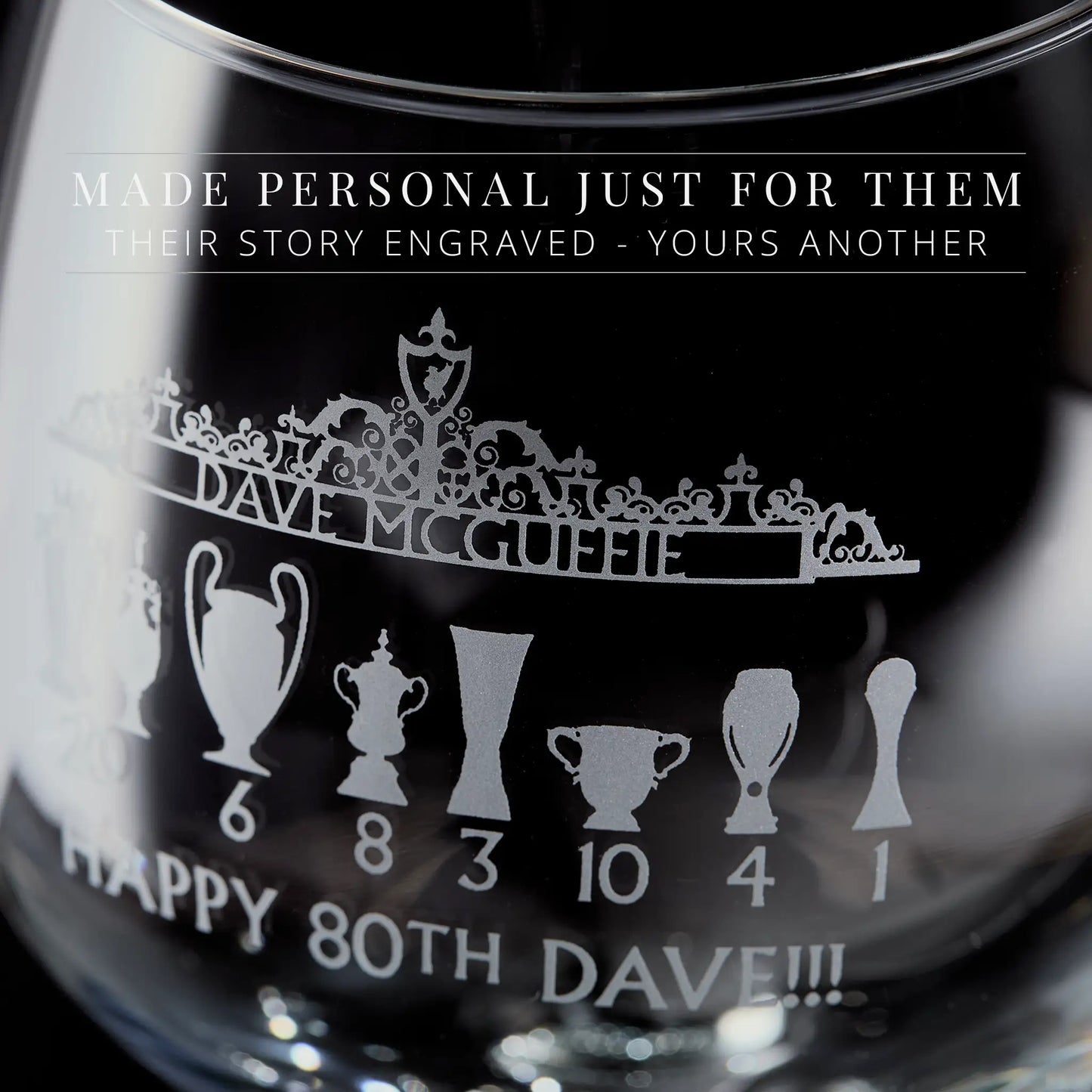 Engraved gin glass featuring the Shankly Gates in line-art style with football trophy silhouettes and personalised text, shown on a black background.