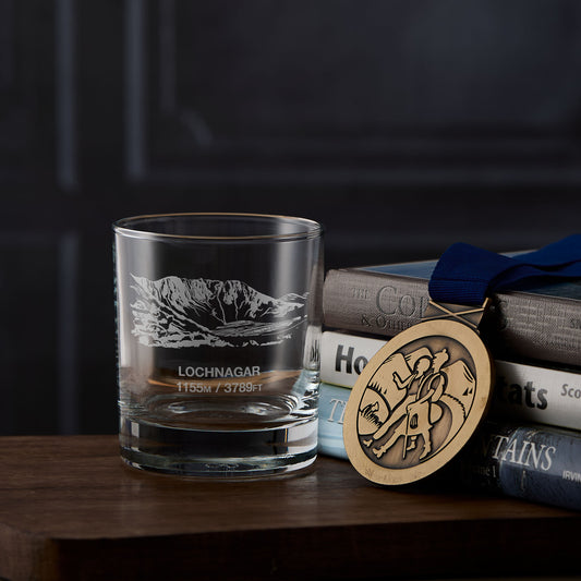 Whisky glass engraved with the North Corrie crags of Lochnagar with hillwalking books on a wooden surface
