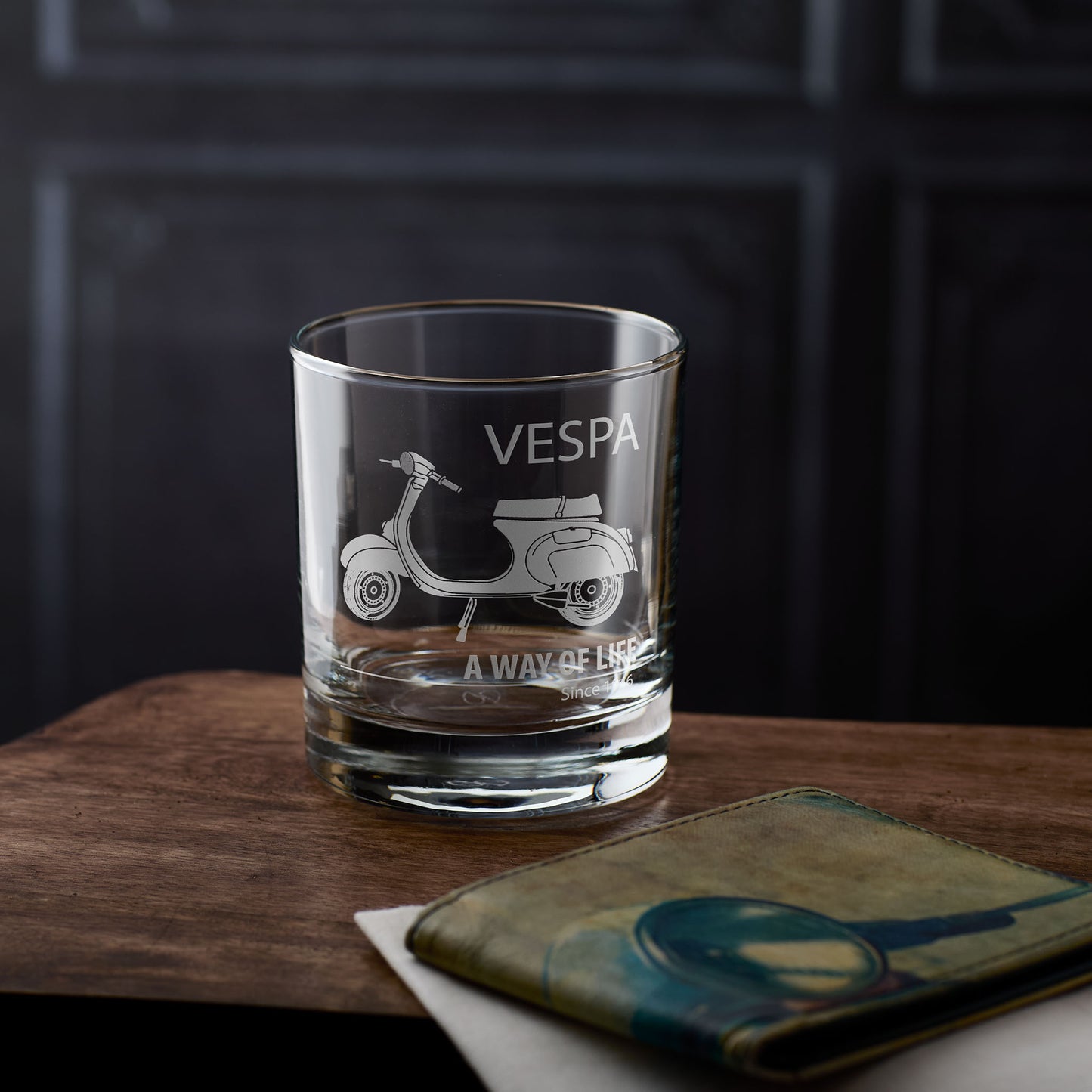 Whisky glass with Vespa Primavera design and personalised text on a wooden surface