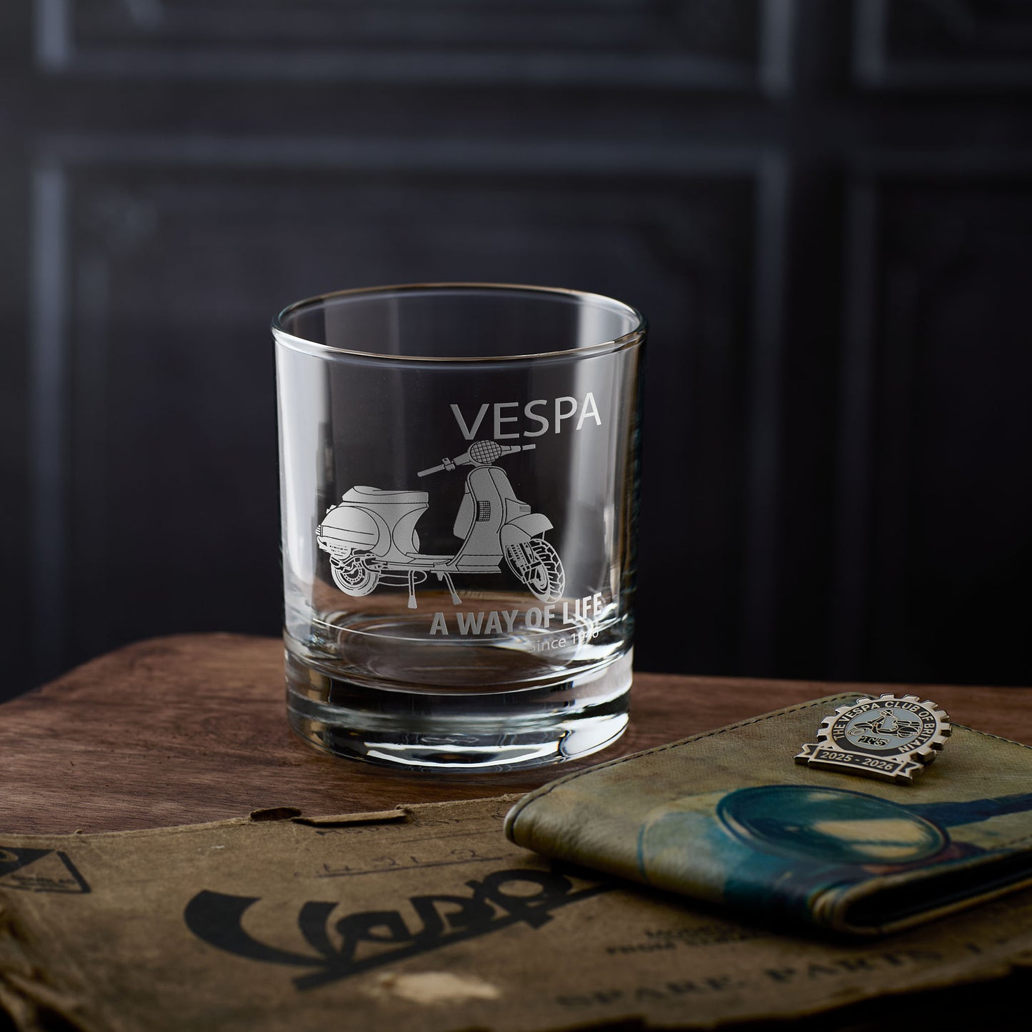 Vespa whisky glass with t5 scooter engraving on a wooden surface with The Vespa Club of Britain badge