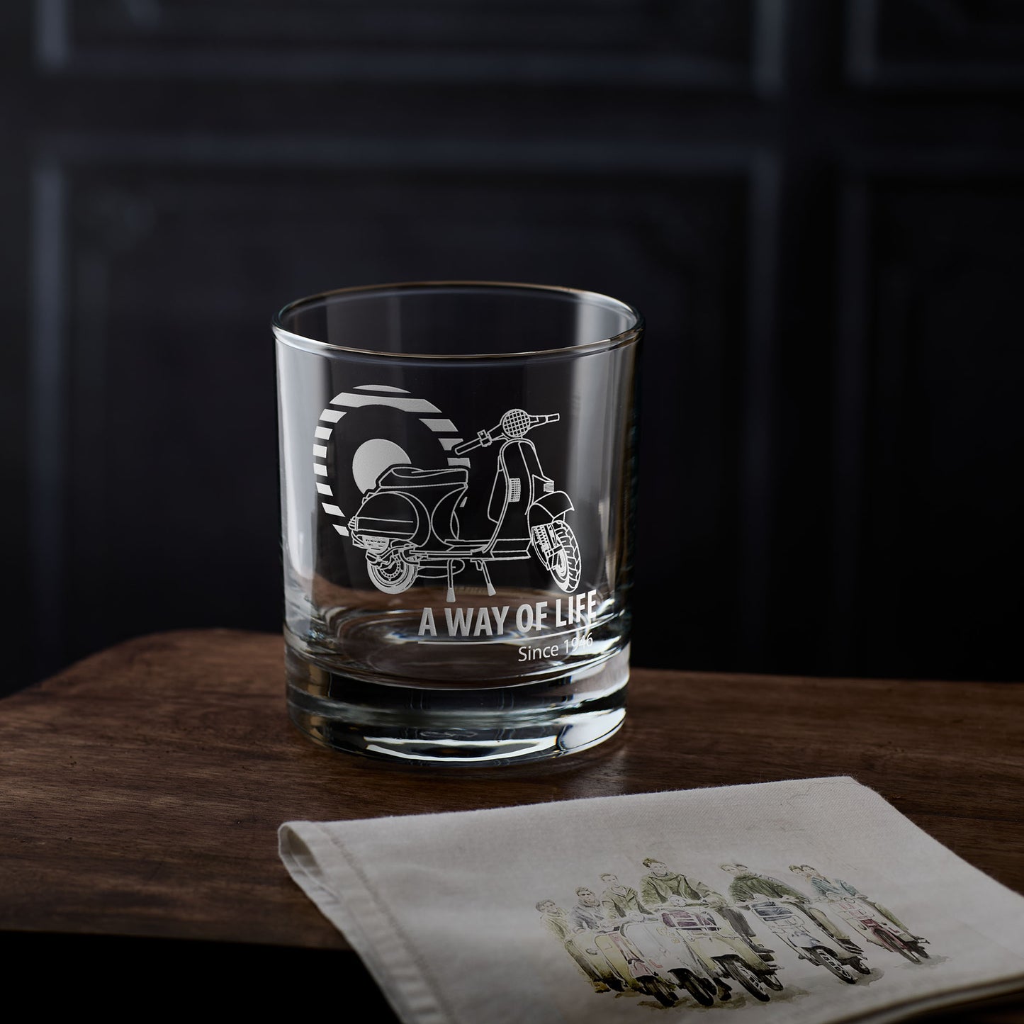 Vespa t5 whisky glass with scooter design and 'A way of Life' text on a wooden surface with a dark background