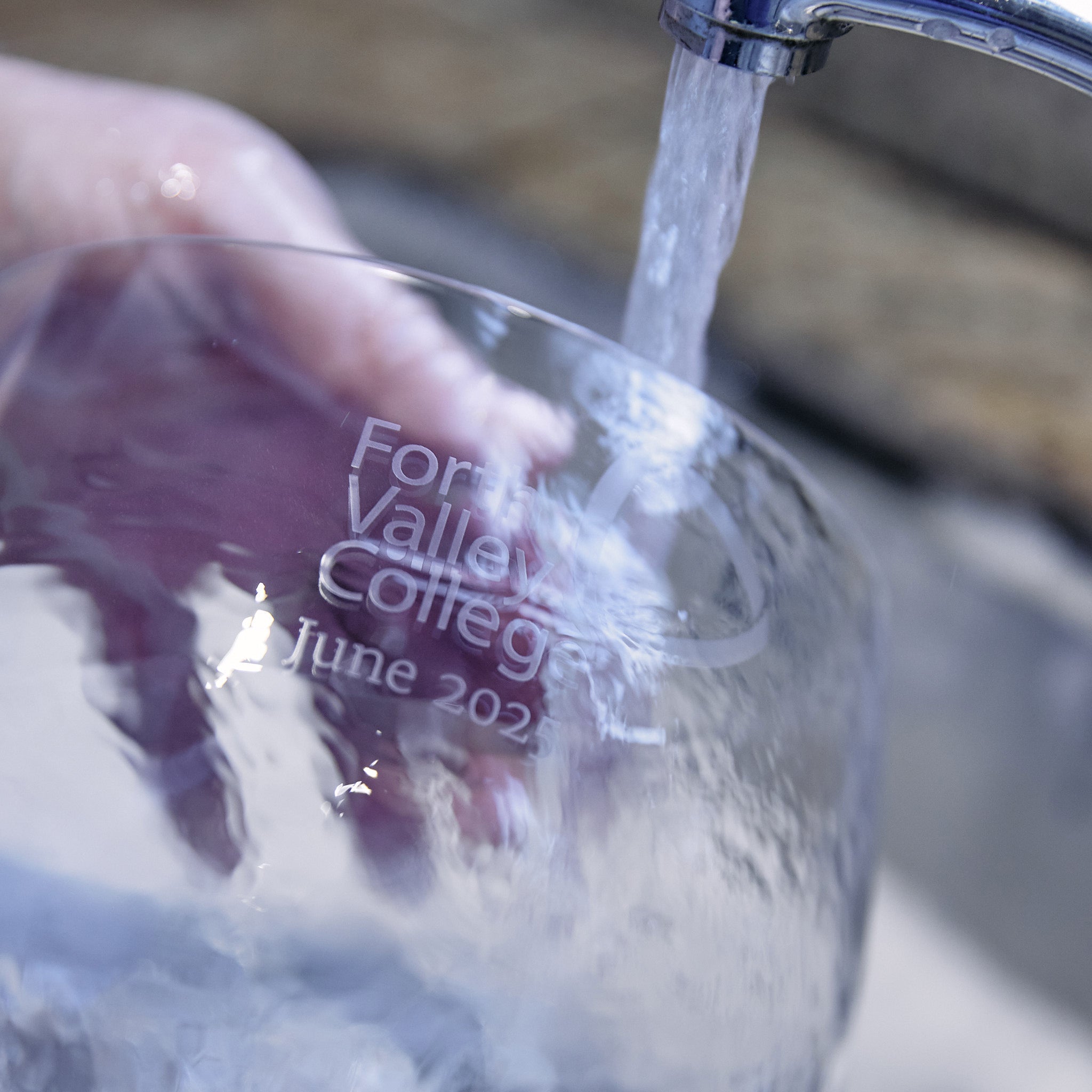 Engraved glass bowl being gently washed to remove stencil, tape, and sandblasting residue after engraving