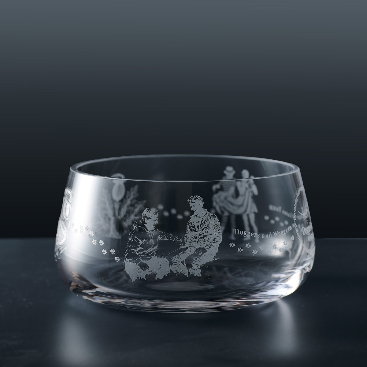 A clear glass bowl with engraved illustrations of dogs and people, with personalised text
