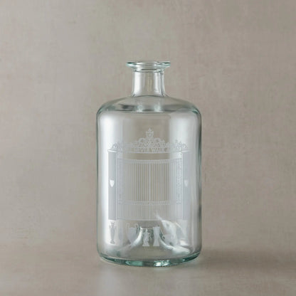 Clear glass bottle with engraved Anfield design on a beige background