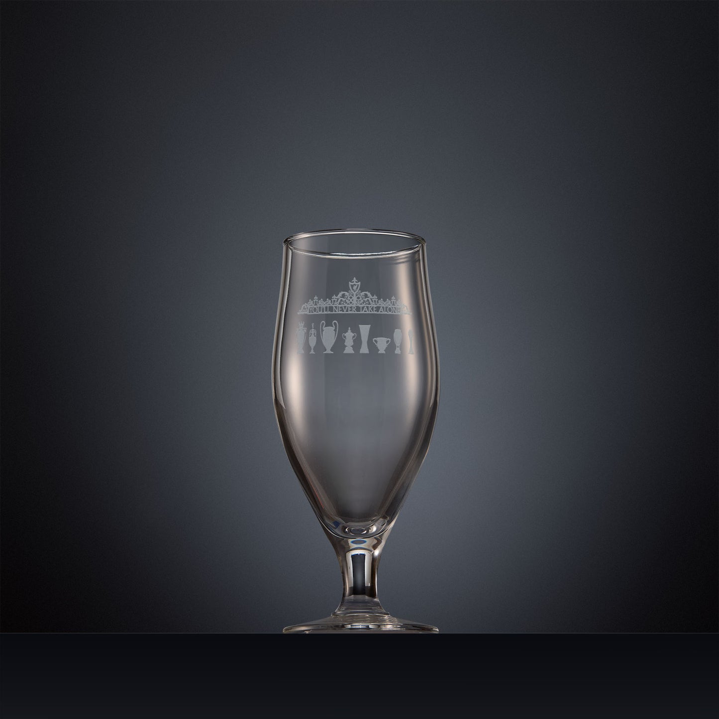 Engraved beer glass featuring the Shankly Gates detail with trophy silhouettes, inspired by Anfield stadium and shown on a dark background