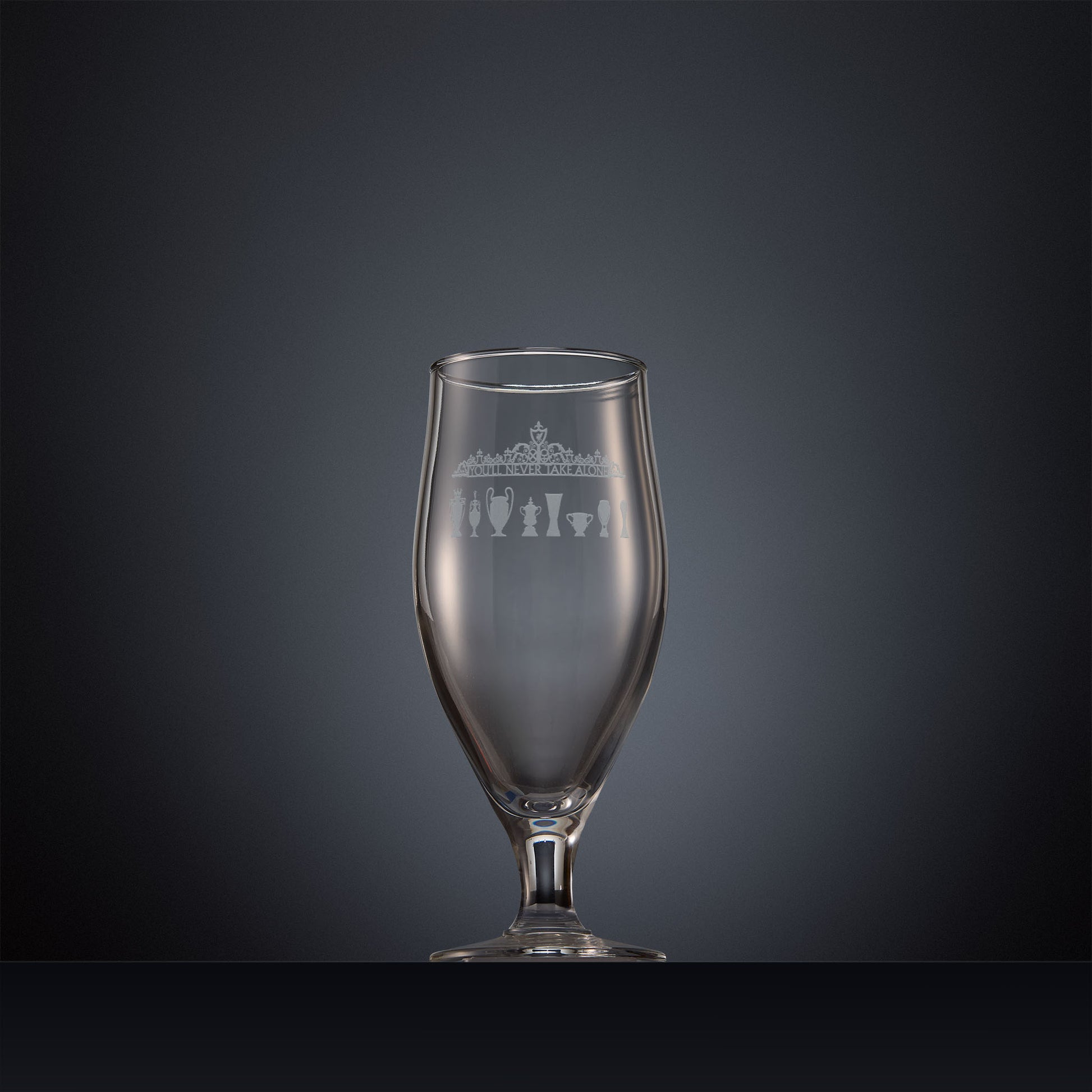 Engraved beer glass featuring the Shankly Gates detail with trophy silhouettes, inspired by Anfield stadium and shown on a dark background