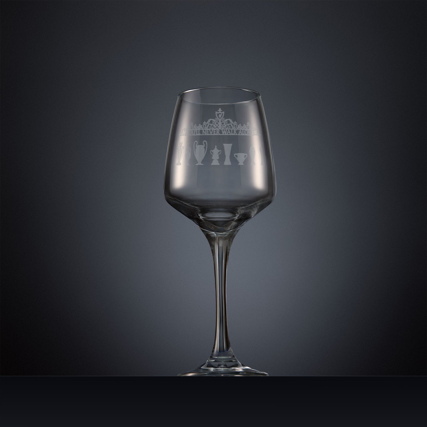 Engraved wine glass featuring the Shankly Gates overthrow with eight trophy silhouettes, shown on a dark background to highlight the fine detail of the sandblasted engraving