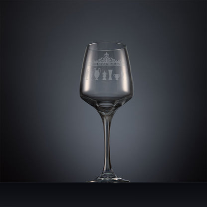 Engraved wine glass featuring the Shankly Gates overthrow with eight trophy silhouettes, shown on a dark background to highlight the fine detail of the sandblasted engraving