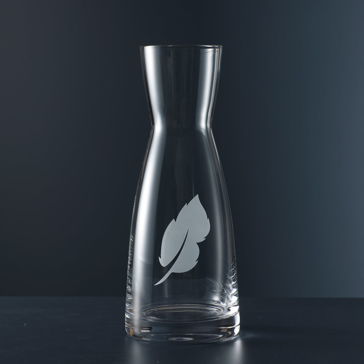 Clear glass carafe with an etched leaf design on the front