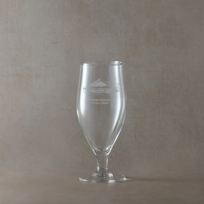 Stemmed beer chalice glass with engraved Beinn Dòrain and text design on a beige background