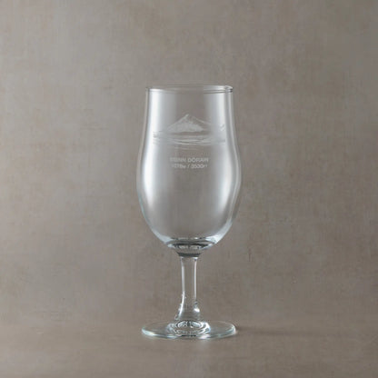 Stemmed beer pint glass with engraved  Beinn Dòrain design on a beige background