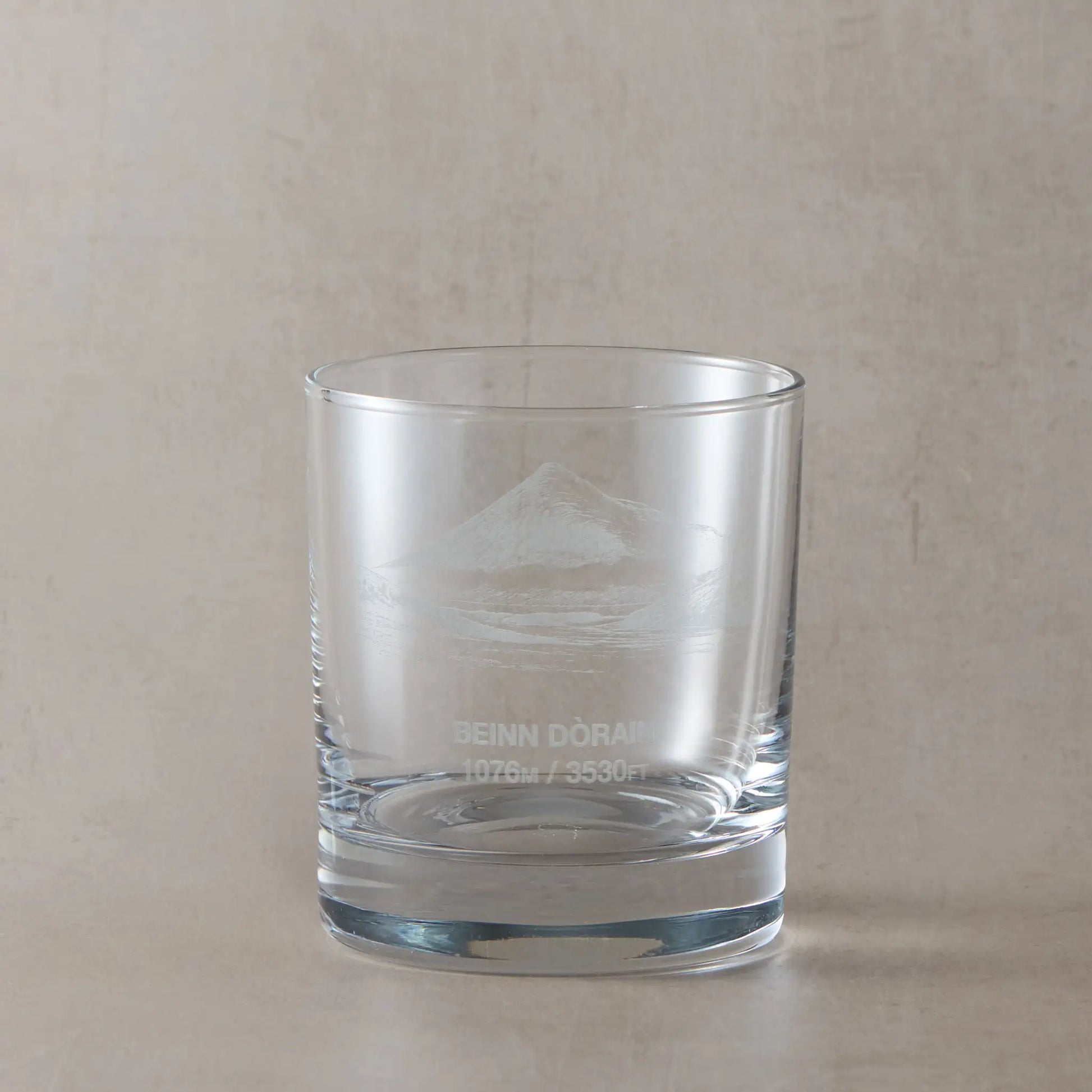 Whisky glass engraved with Beinn Dorain, photographed on a pale beige background