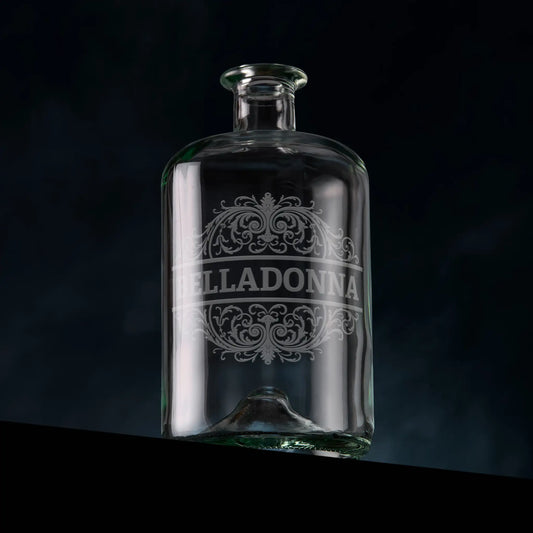 Clear glass apothecary bottle engraved with 'Belladonna' and baroque design on a dark background