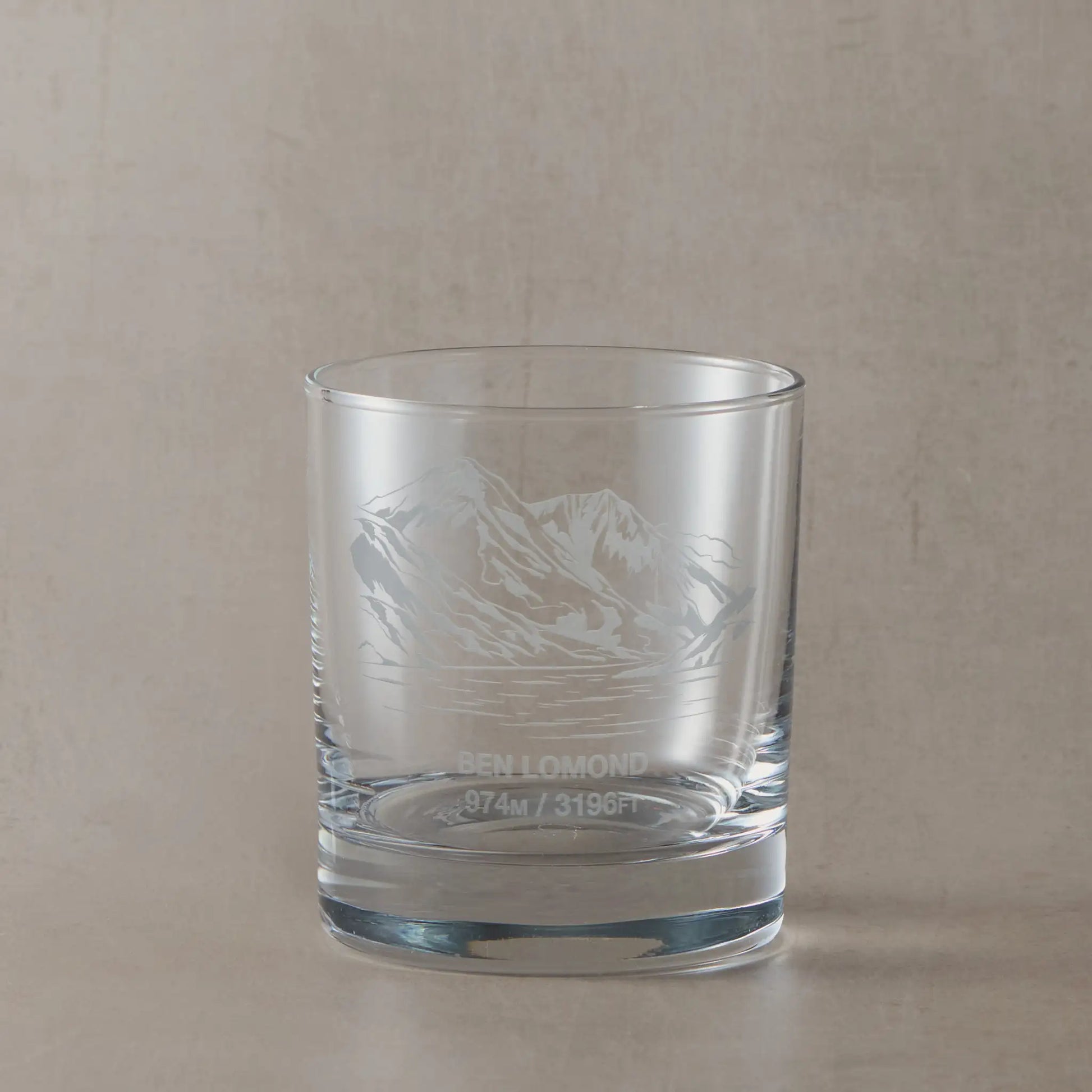 Whisky glass with engraved Ben Lomond design on a beige background