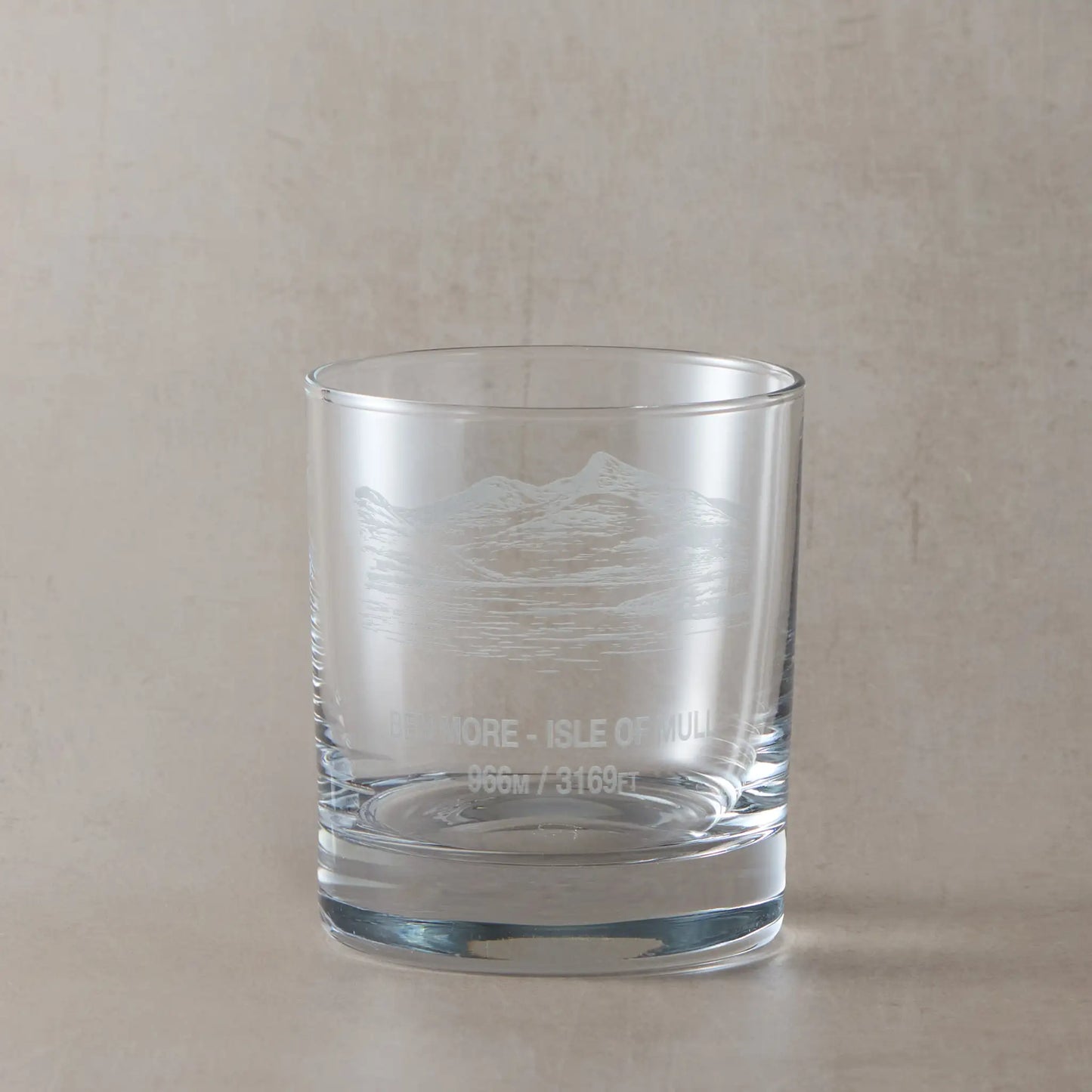 Whisky glass engraved with the Scottish mountain Ben More, styled on a beige background
