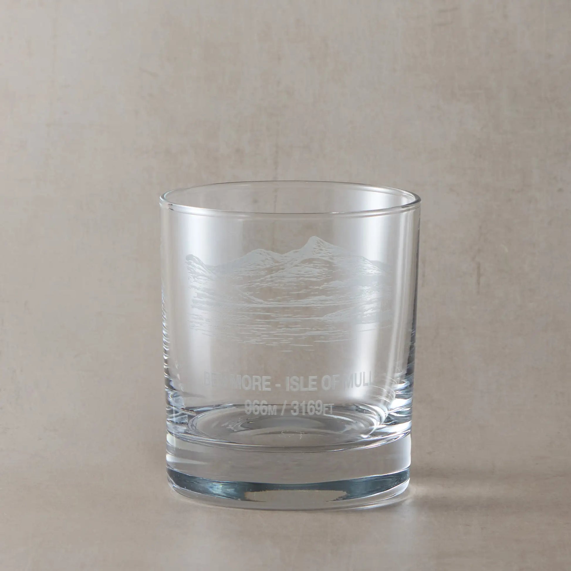 Whisky glass engraved with the Scottish mountain Ben More, styled on a beige background