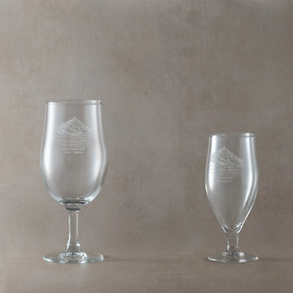 Two stemmed beer glasses with engraved Ben Vorlich mountain on a beige background
