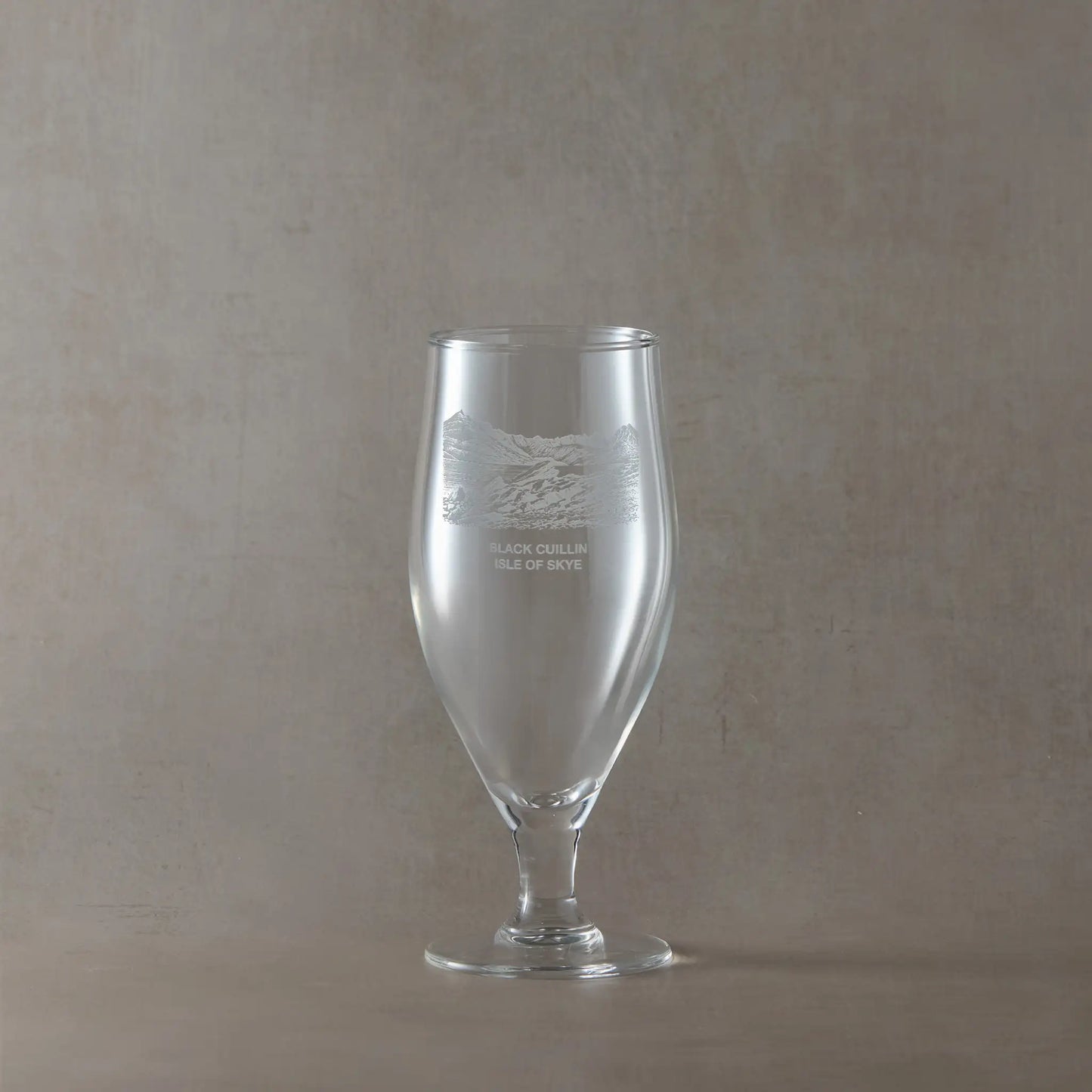 Stemmed chalice beer glass engraved with the Back Cuillin on a beige backgroud