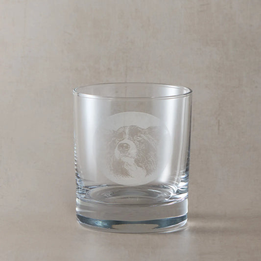 Whisky glass with engraved portrait of a Border Collie on a beige background