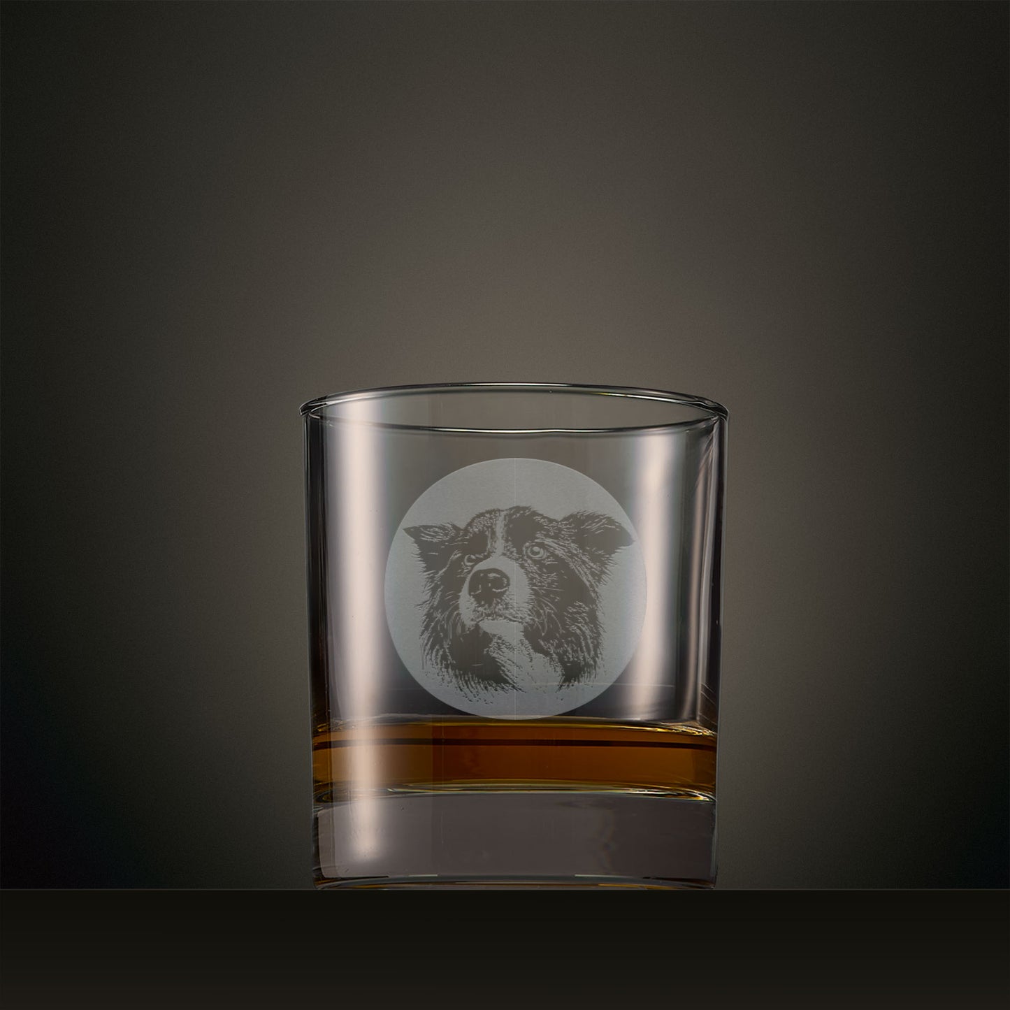Engraved whisky glass featuring a Border Collie portrait set within a circular design, photographed on a studio background