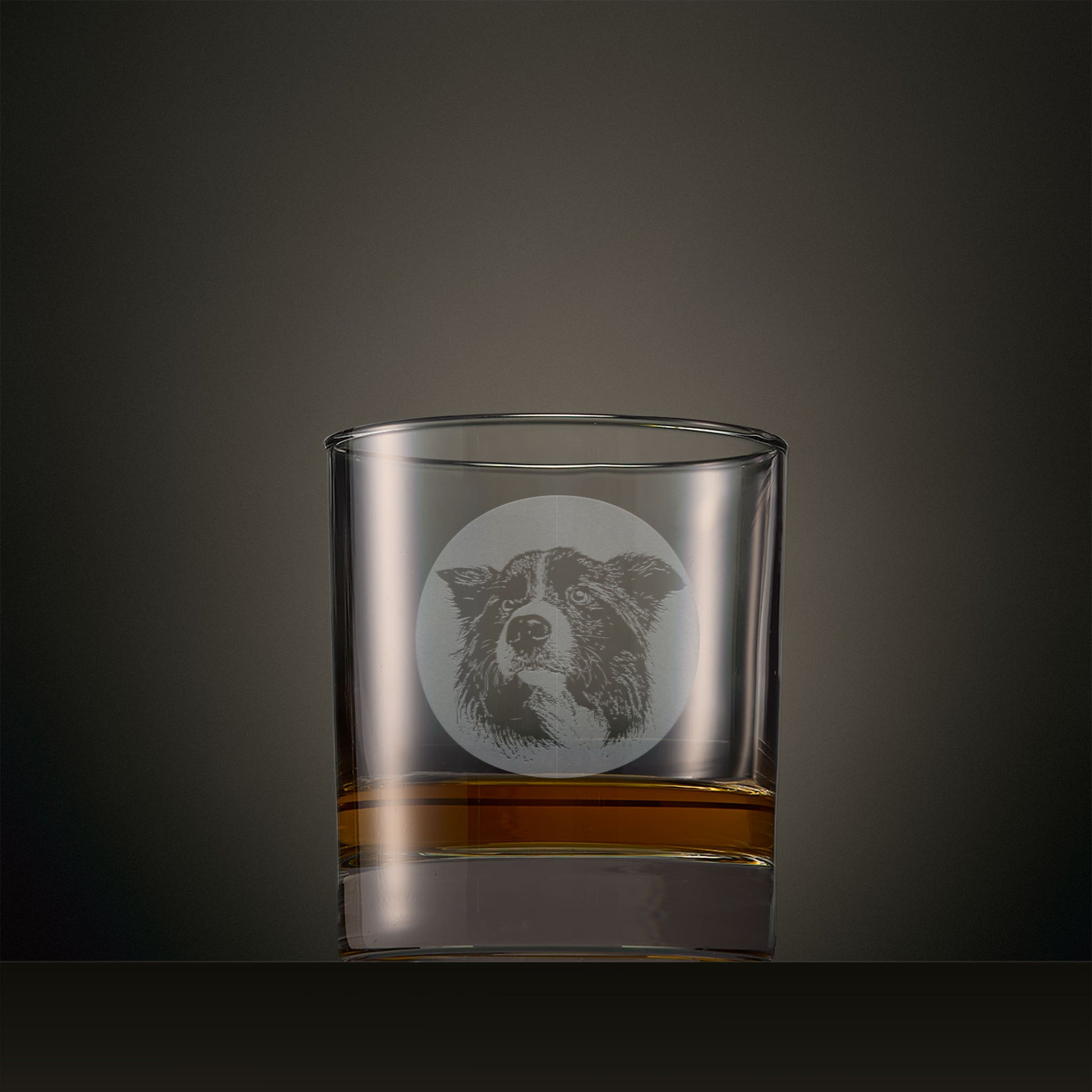 Engraved whisky glass featuring a Border Collie portrait set within a circular design, photographed on a studio background