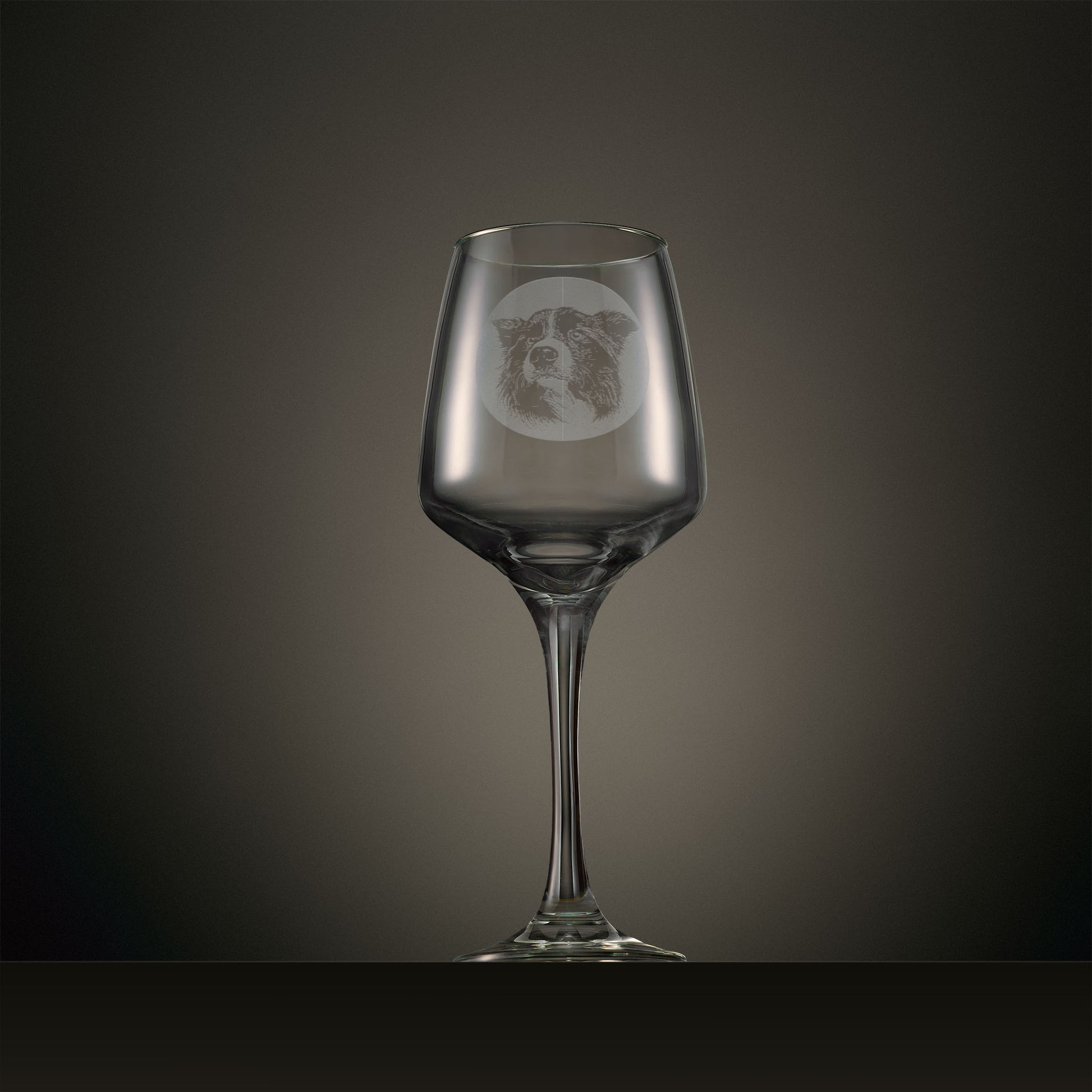 Engraved wine glass featuring a portrait Border Collie design, shown on a dark studio background