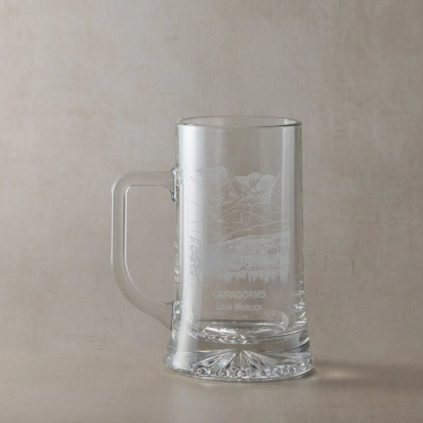 Engraved tankard with Cairngorms and Loch Morlich design shown on beige background, handle on left of engraving