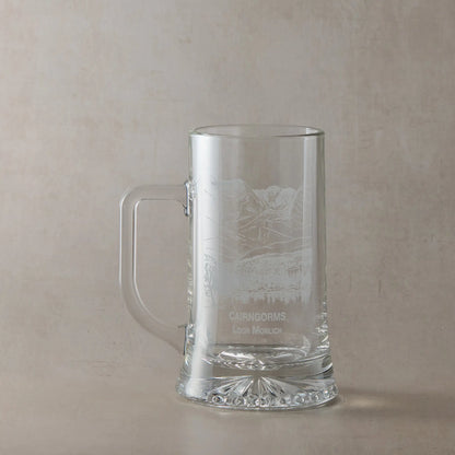 Engraved tankard with Cairngorms and Loch Morlich design shown on beige background, handle on left of engraving