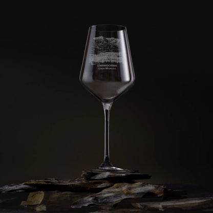 Engraved wine glass featuring the Cairngorms and Loch Morlich landscape, shown on a dark studio background with a detailed mountain and waterline design