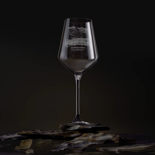 Engraved wine glass featuring the Cairngorms and Loch Morlich landscape, shown on a dark studio background with a detailed mountain and waterline design