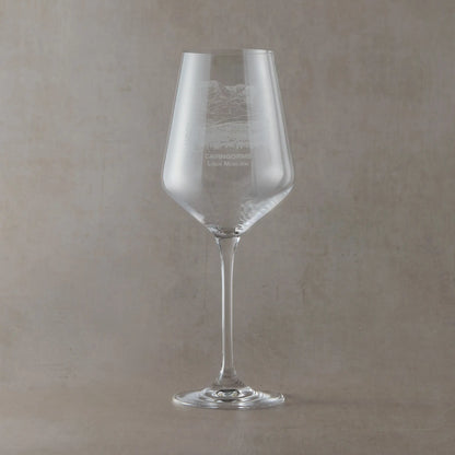 Clear wine glass with engraved Loch Morlich and Cairgorms design on a beige background