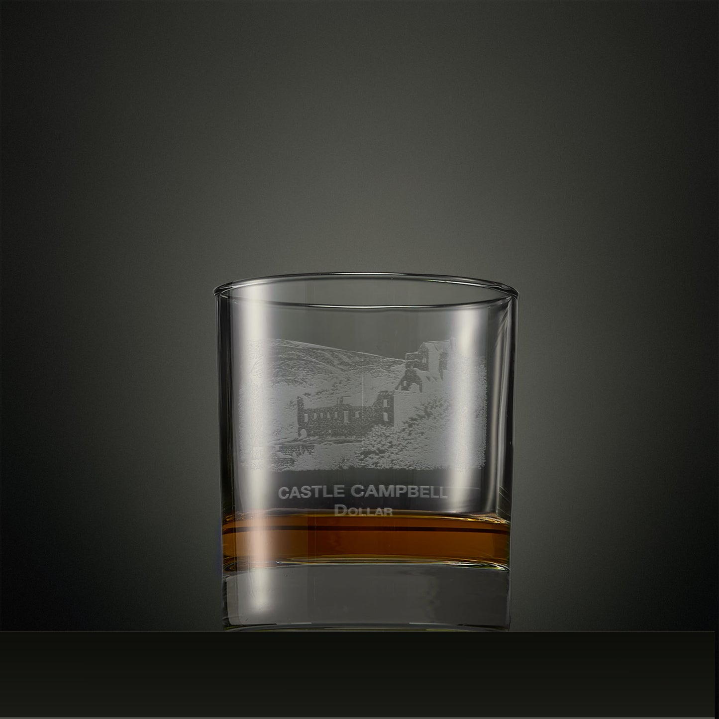 Clear whisky glass with engraved castle Campbell design on a dark background