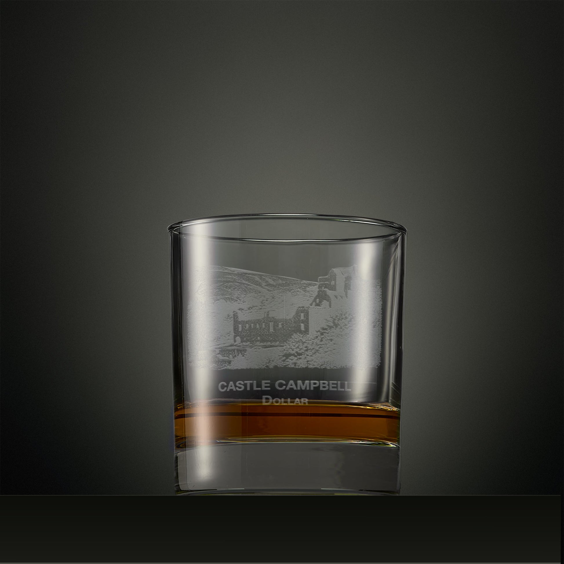 Clear whisky glass with engraved castle Campbell design on a dark background