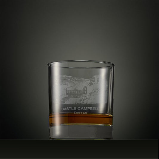 Clear whisky glass with engraved castle Campbell design on a dark background