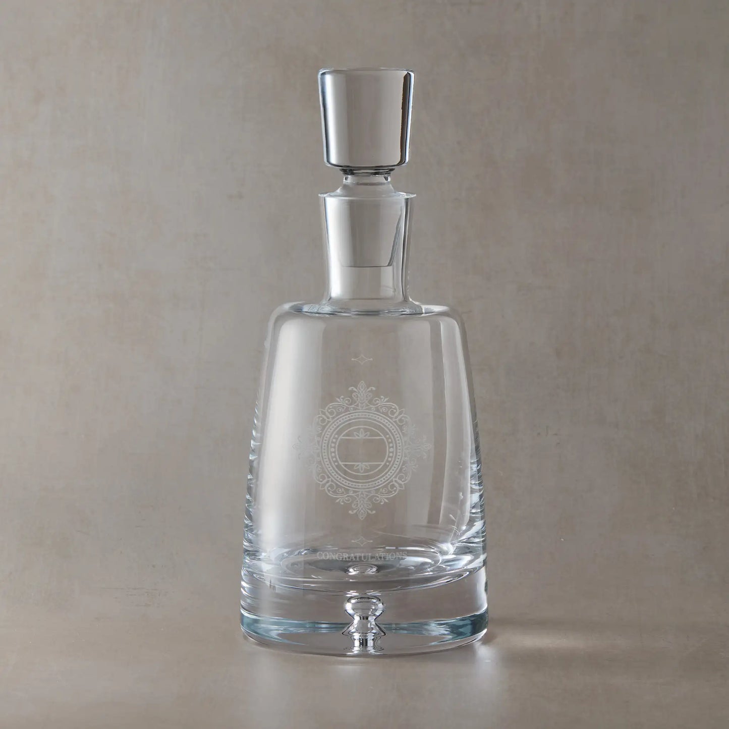 Clear glass decanter with engraved Chantilly Lace design on a beige background